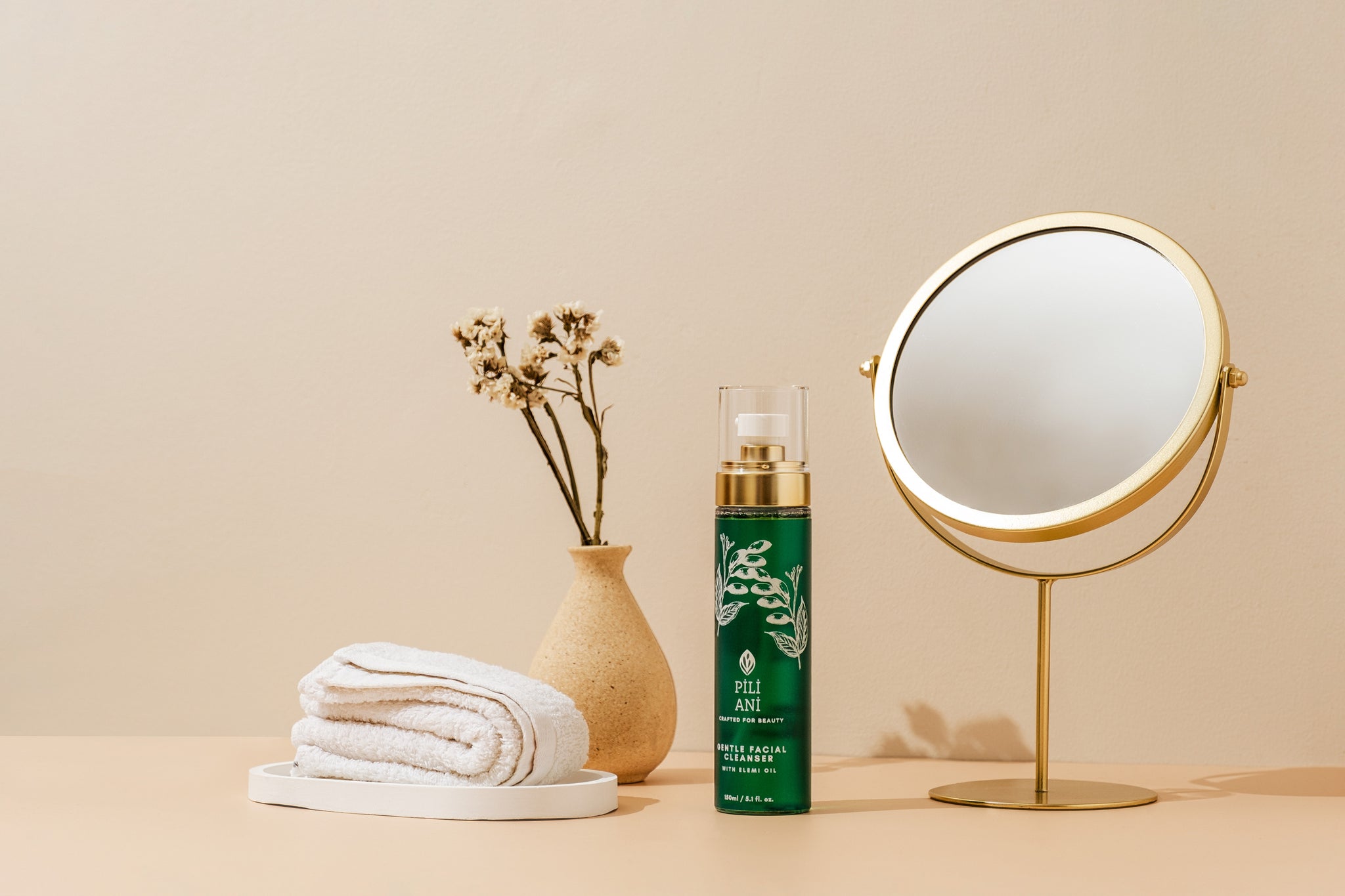 A bottle of the Pili Ani Gentle Facial Cleanser placed beside a towel, vase, and mirror Pili Ani Gentle Facial Cleanser, $32.