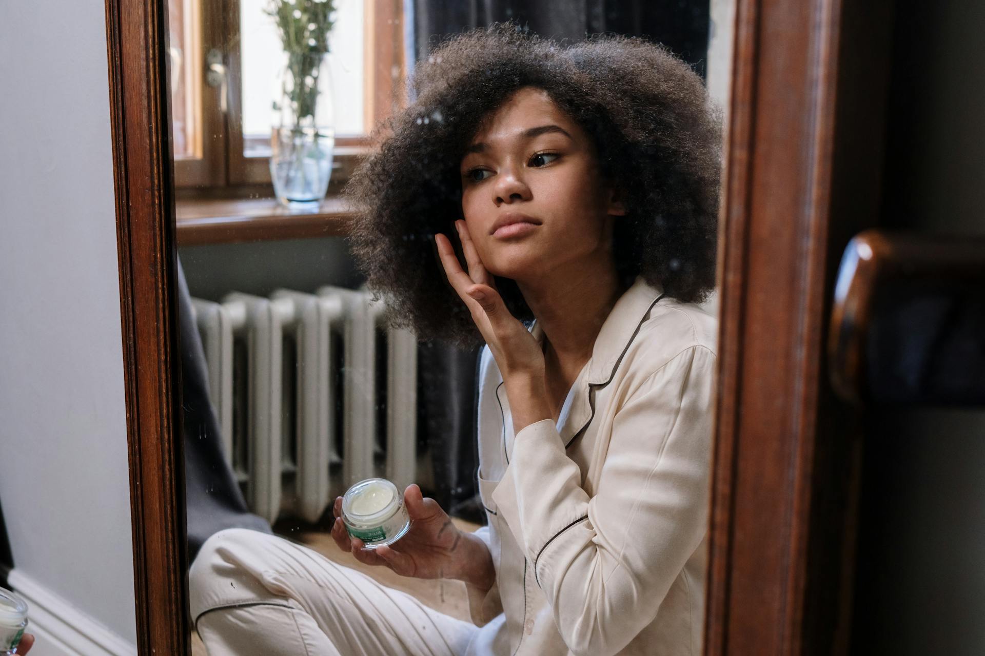 Woman applying skin care product on face